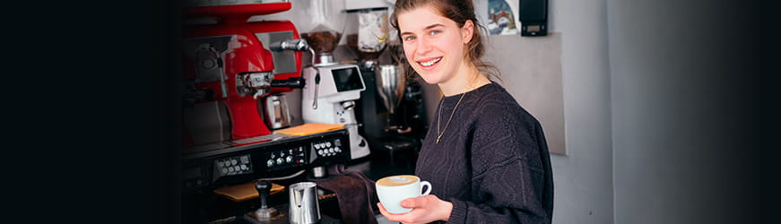 Jeune fille souriante devant la machine à café dans un restaurant