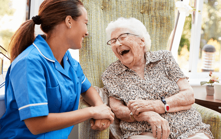 Infirmière en transition de carrière discute et rigole avec une patiente âgée 