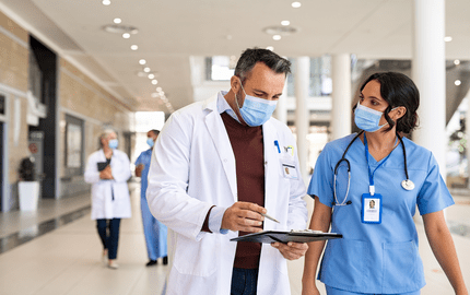 deux professionnels de santé vacataires qui discutent ensemble, le médecin avec une blouse blanche montre à sa collègue quelque chose sur son calepin