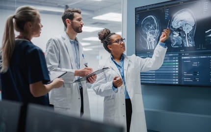 cadre de santé montre une radio d’un patient à ses collègues radiologues sur un tableau connecté dans un hôpital