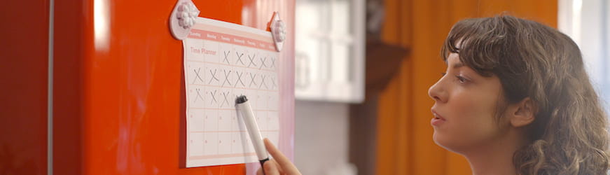 Une future maman qui compte le nombre de jours de son prochain congé maternité, sur un calendrier accroché à un frigo
