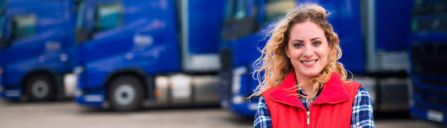 Jeune femme posant devant une flotte de camions d’une entreprise de transport-logistique