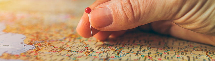 Une main posée une épingle sur une carte de France