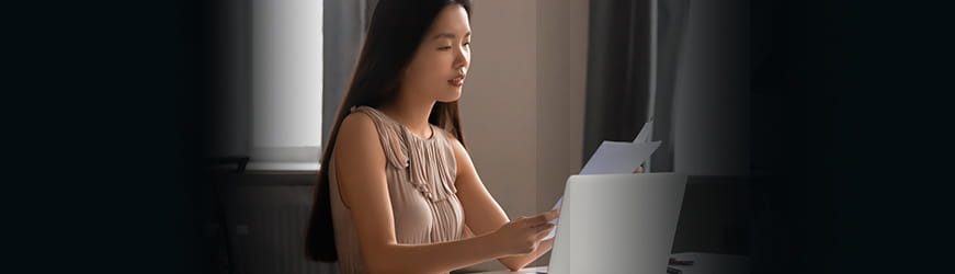 une jeune femme qui regarde les pages d’un test devant un ordinateur