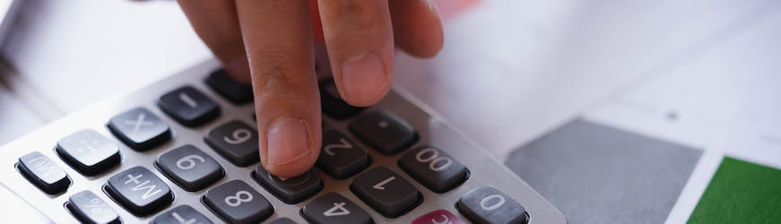 Les mains d’une personne en train de taper sur les touches d’une calculatrice, au moment d’effectuer sa déclaration de revenus