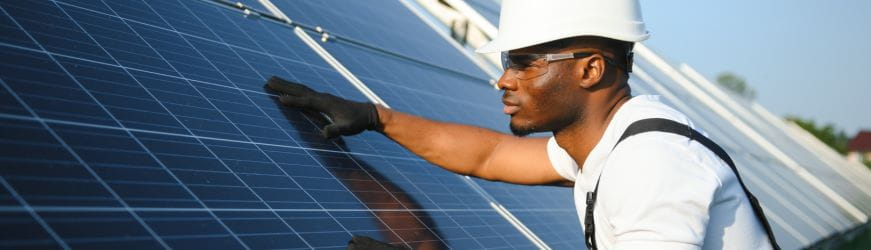 Un jeune homme travaillant dans le BTP en train de poser des panneaux solaires.