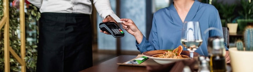 Une salariée en déplacement professionnel, qui paye un repas au restaurant avec sa carte bleue.