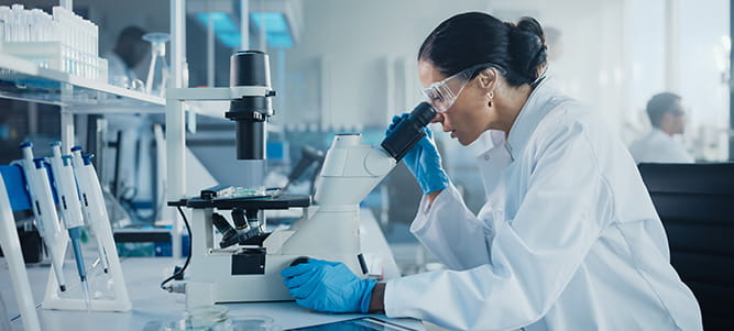 femme devant un microscope observe des cellules souches dans le cadre de ses travaux de recherche dans le domaine de la santé