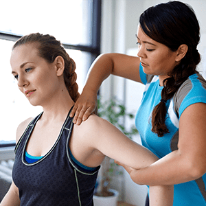 Femme kiné en train de masser l'épaule d'une patiente dans un cabinet kiné Offre infirmier.e