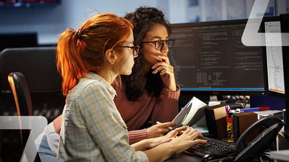 deux femmes devant un écran, révisent le code d’une page web dans le cadre d’un projet IT
